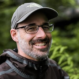 A man wearing glasses, a hat, and a raincoat